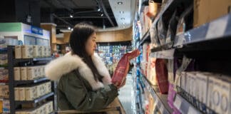 A young woman considers dog food labels looking at its digestibility.