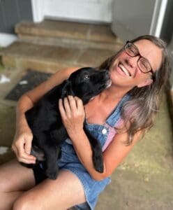 Happy dog owner with a puppy in her lap.