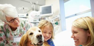 Young girl in hospital hugging therapy dog