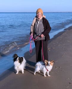 Whole Dog Editor Cindy Foley walking two paillons on the beach.