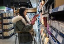 A woman browses for pet food in a grocery store aisle.