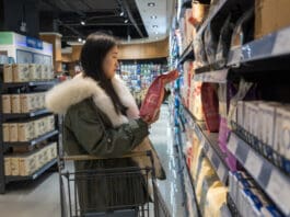 Pros and Cons of Large Pet Food Companies A woman browses for pet food in a grocery store aisle.